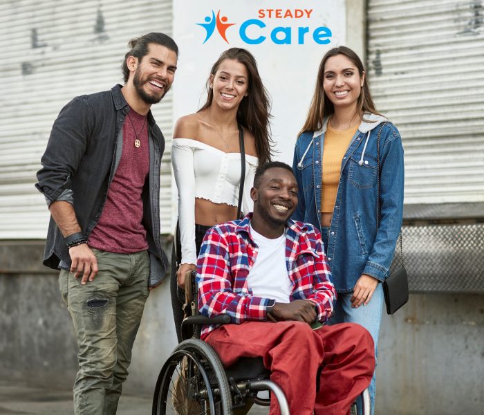 Smiling African-American man in a wheelchair with Hispanic friends in outdoor urban Los Angeles setting.